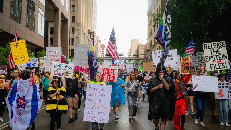 Demonstrators march through the streets of downtown despite heavy rain for the No King Day.