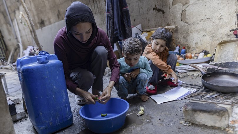 Sabah Abu Ghanem prepares food with her children in a makeshift kitchen in Gaza City.