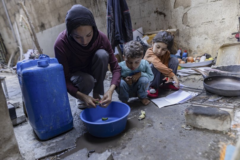 Sabah Abu Ghanem prepares food with her children in a makeshift kitchen in Gaza City, Gaza Strip.