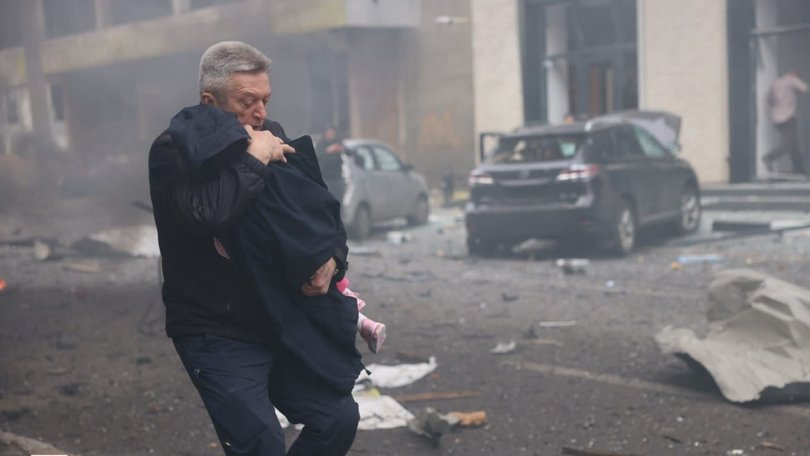 A man holds a child after the Russian drone strike on a kindergarten in Kharkiv, Ukraine on October 22, 2025.