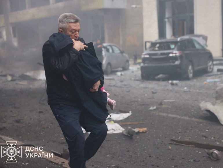A man holds a child after the Russian drone strike on a kindergarten in Kharkiv, Ukraine on October 22, 2025. 
