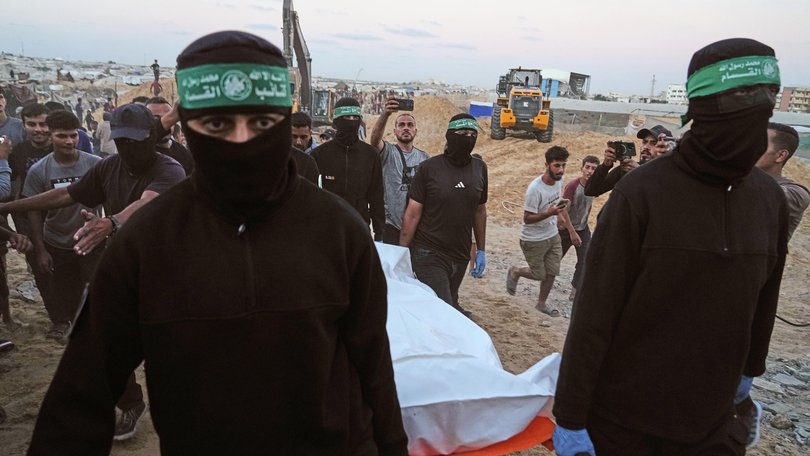 Hamas militants carry a white bag believed to contain a body, during a search for the remains of hostages in Hamad City, Khan Younis, in southern Gaza, on Tuesday, October 28, 2025.