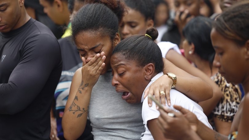 People cry on a street where dead bodies are gathered in Rio de Janeiro, Brazil.