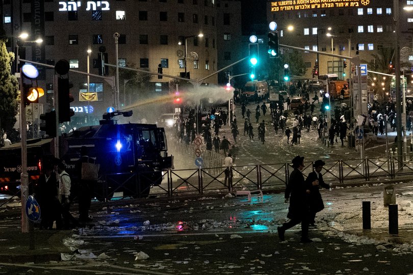 Police officers use water cannon to disperse Ultra Orthodox Jewish men.
