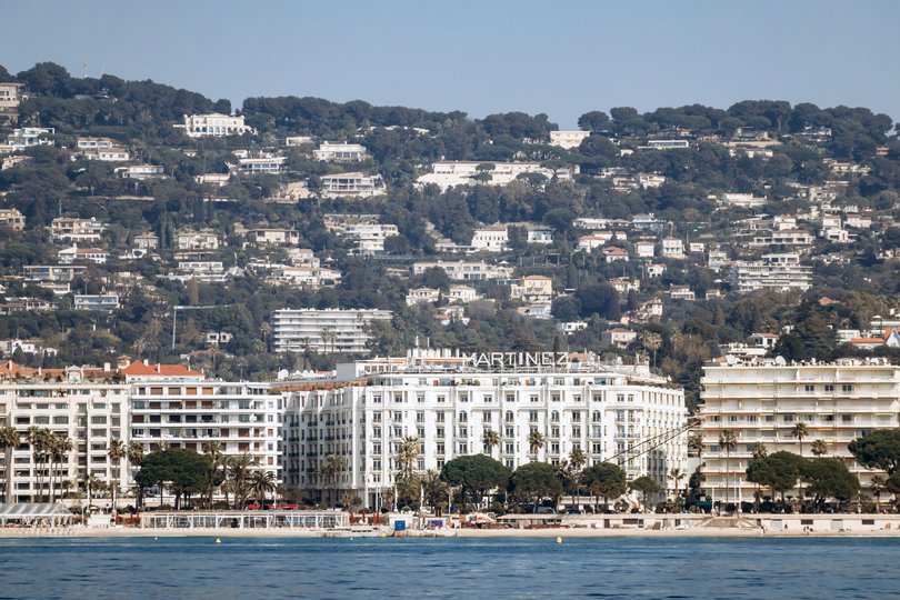 Iconic Hôtel Martinez on La Croisette with hillside villas in the background.