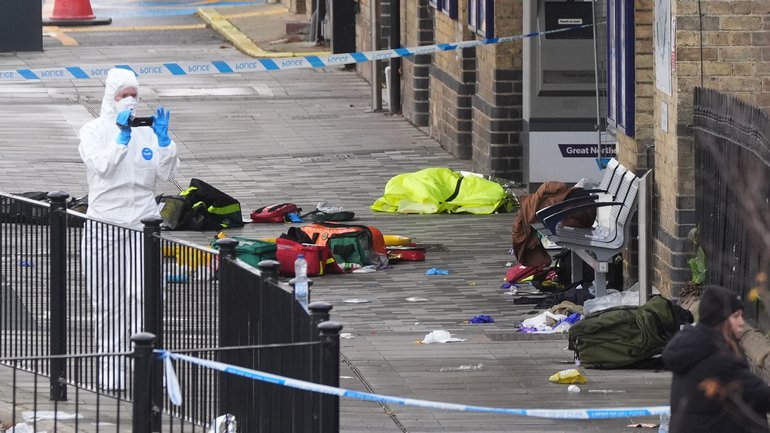 A forensic investigator films the area where travellers left their belongings at Huntingdon Station after a mass stabbing on a London-bound train. (Joe Giddens/PA via AP)
