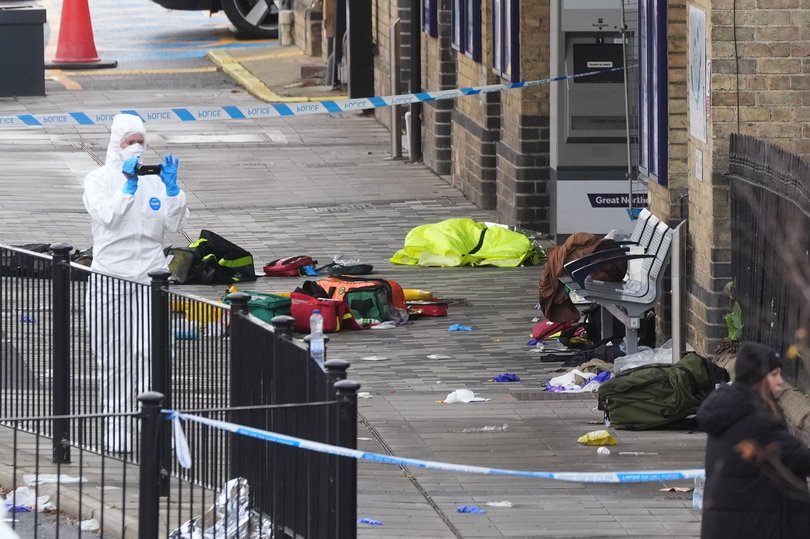 A forensic investigator films the area where travellers left their belongings at Huntingdon Station after a mass stabbing on a London-bound train. (Joe Giddens/PA via AP)
