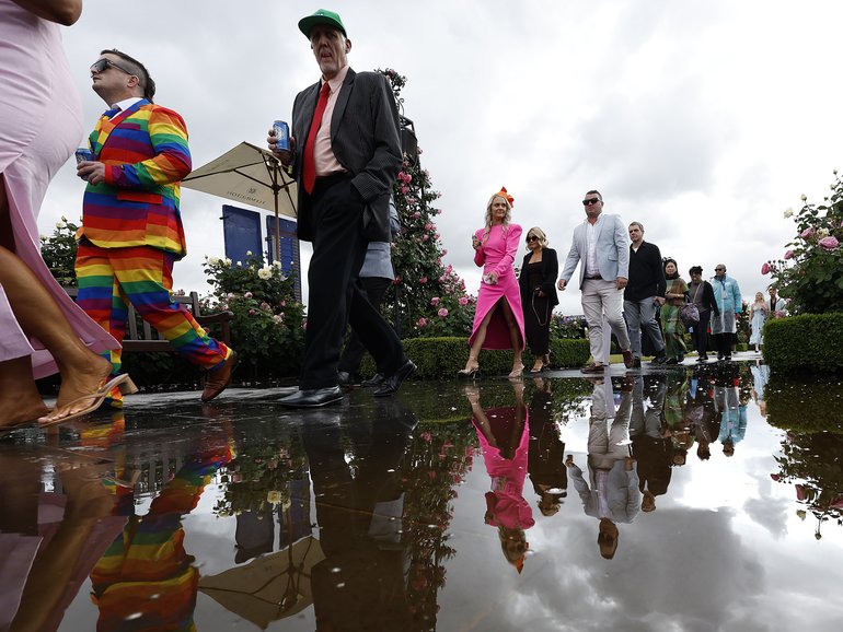 Racegoers walk by rainwater water at Flemington Racecourseto get to the 2025 Melbourne Cup.