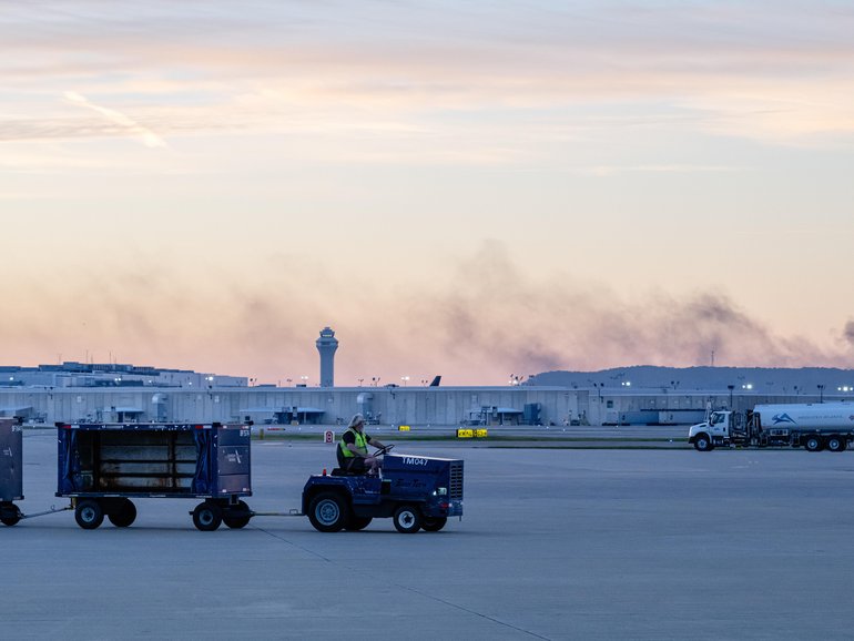 The ATC tower is seen while smoke continues to rise from the crash site of UPS Flight 2976 near Louisville Muhammad Ali International Airport.