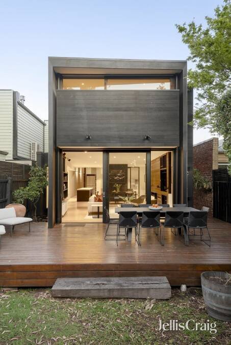 The landscaped backyard with deck, mature trees and lawn.
