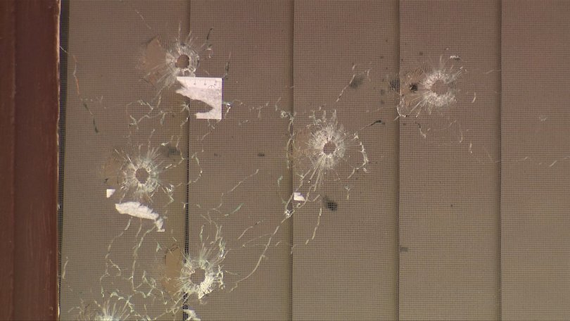 Several bullet holes in the window of one of the homes.