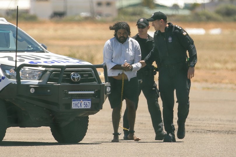 Terence Darrell Kelly boards a plane after being taken into custody.