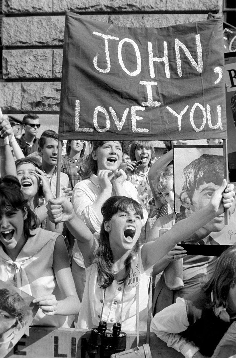 Screaming Beatles fans cheer for their idols on the streets of New York City.