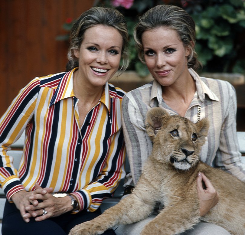 The Kessler twins, the famous twins of the German show business, who were active as singers, dancers, actresses and entertainers, posing together for a photo with a lion cub, circa 1970s.