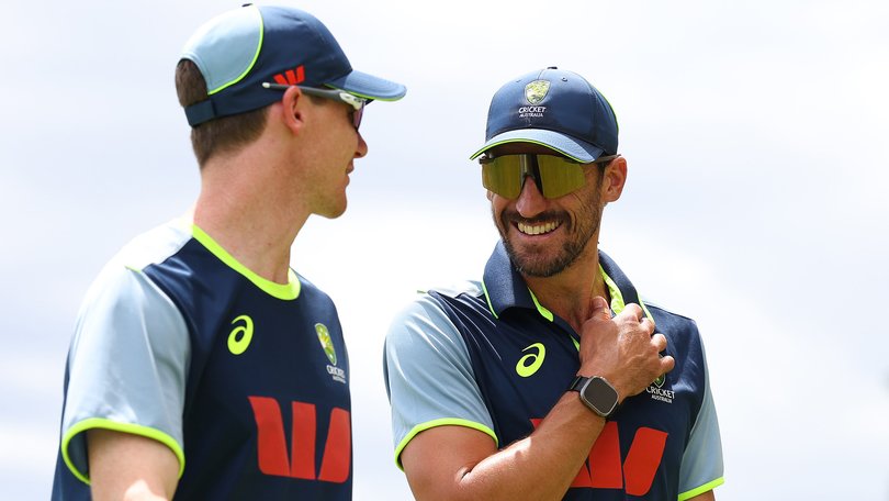 Brendan Doggett and Mitchell Starc walk from the nets area after nearby lightning halts the practice session.