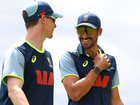 Brendan Doggett and Mitchell Starc walk from the nets area after nearby lightning halts the practice session.