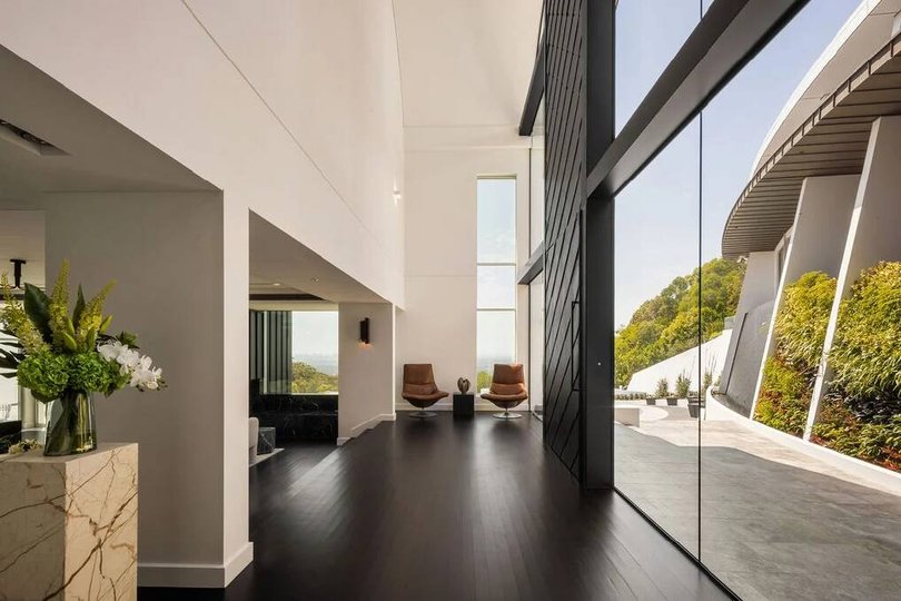 The house features curved architectural rooflines, full-height glass and tundra-grey limestone.