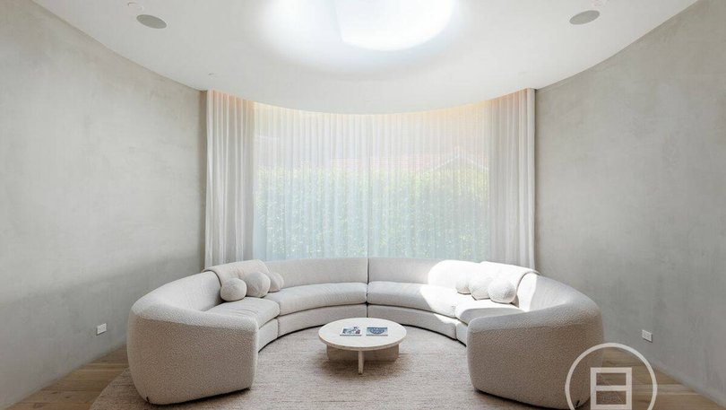 A wall of curved glass frames views of the garden and juxtaposes the geometry of the architecture.