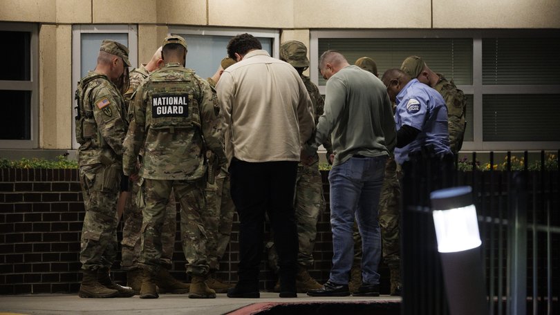 National Guard members participate in a group prayer with civilians and a security officer outside the emergency entrance to MedStar Washington Hospital Center on Wednesday after two Guard members were shot earlier in the day. 