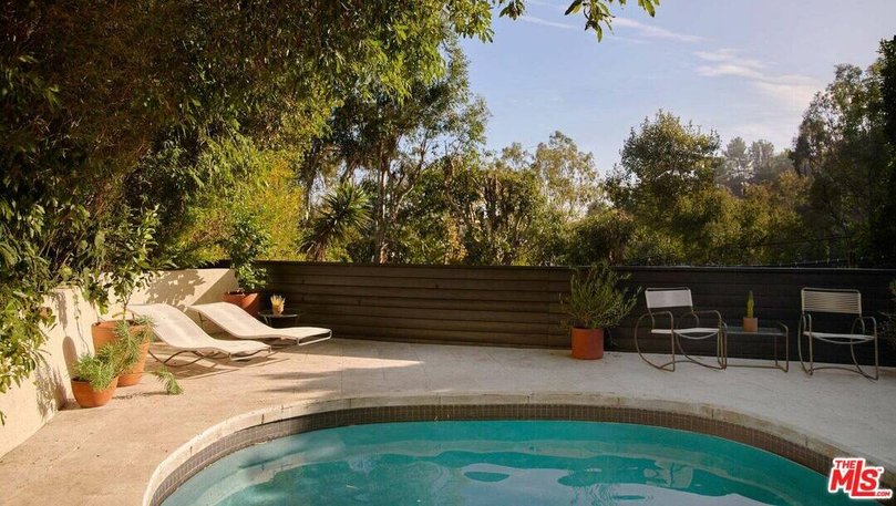 Glass doors lead out onto an outdoor patio, complete with firepit and swimming pool. Pic: Compass.