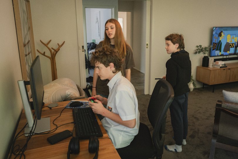 Darcey Pritchard, background, who deleted Snapchat off her phone about a year ago when she felt sucked in by its algorithm, watches as her brother plays a computer game.