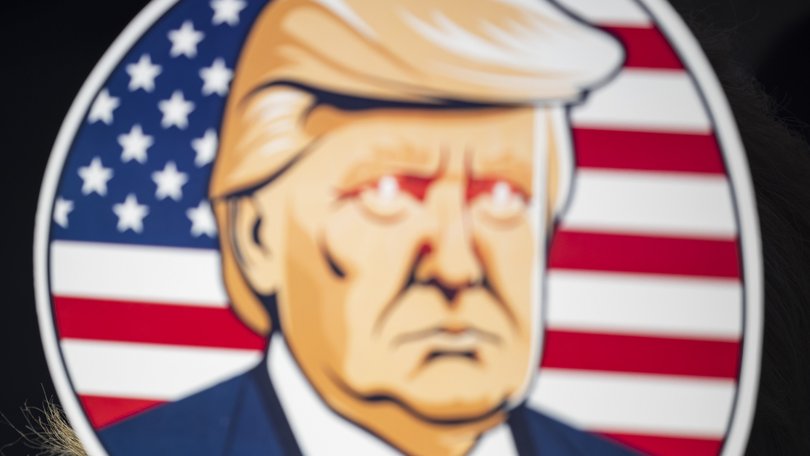 A woman holds up a fan depicting then-former President Donald Trump an an election campaign rally in Latrobe, Pa., on Oct. 19, 2024.