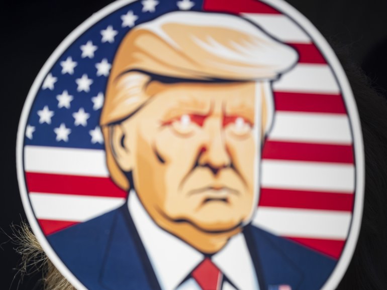 A woman holds up a fan depicting then-former President Donald Trump an an election campaign rally in Latrobe, Pa., on Oct. 19, 2024.