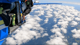 Skydiver hangs from plane tail, snared by own chute.