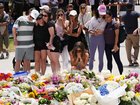People gather around a growing flower tribute to shooting victims outside the Bondi Pavilion at Sydney's Bondi Beach.