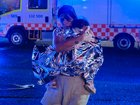 A member of the public leaves the scene with her child, who is covered in an emergency blanket, after the shooting at Bondi Beach.