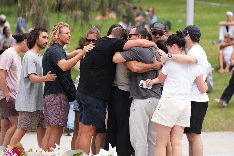 People embrace after laying flowers at a memorial outside Bondi Pavilion at Sydney's Bondi Beach.