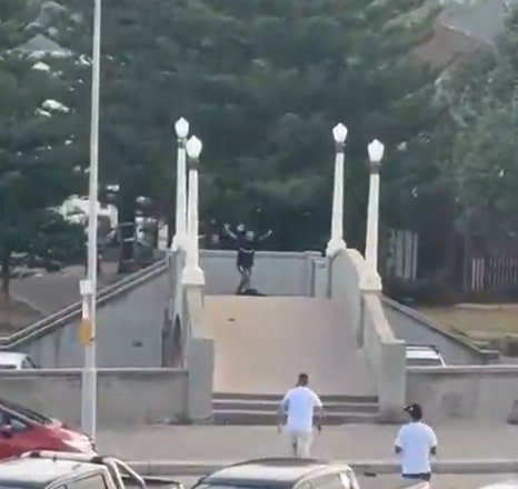 The Bondi shooter is approached by a man after he has been shot by police, who is filmed kicking the gun away.