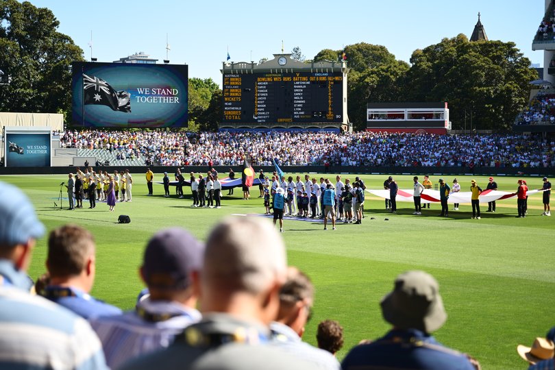 Players, officials and spectators stand to observe a moment’s silence.