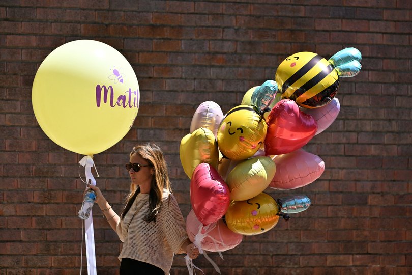 A mourner carries balloons while arriving for the funeral of 10-year-old Matilda.