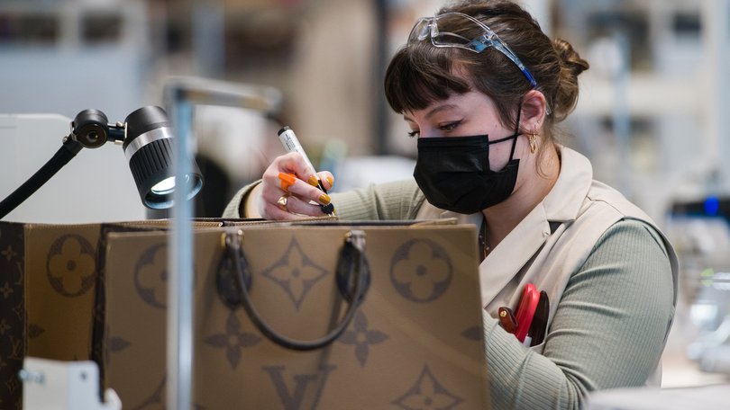 An employee glues a piece of leather while making a luxury Louis Vuitton handbag in the Oratory Workshop at the Atelier Louis Vuitton Vendome in Vendome, France. 