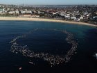 Members of the Bondi community paddle and swim into the ocean and form a circle to pay their respects.