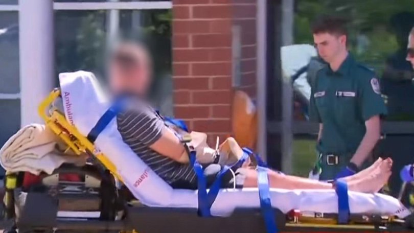 A man is taken to hospital with bags on his hands from the Aldinga Police station. Picture: 7NEWS