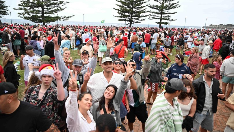 Backpackers and expats dressed in Santa hats and red swimwear packed the sand for an unofficial Christmas Day gathering. Picture: NewsWire / Monique Harmer