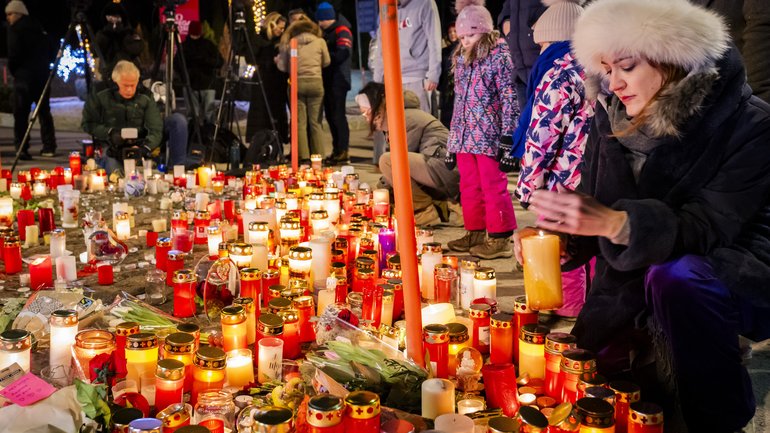 People pay their respects to the victims with flowers and candles near the area where a fire broke out during the New Year's celebrations in Crans-Montana, Switzerland.
