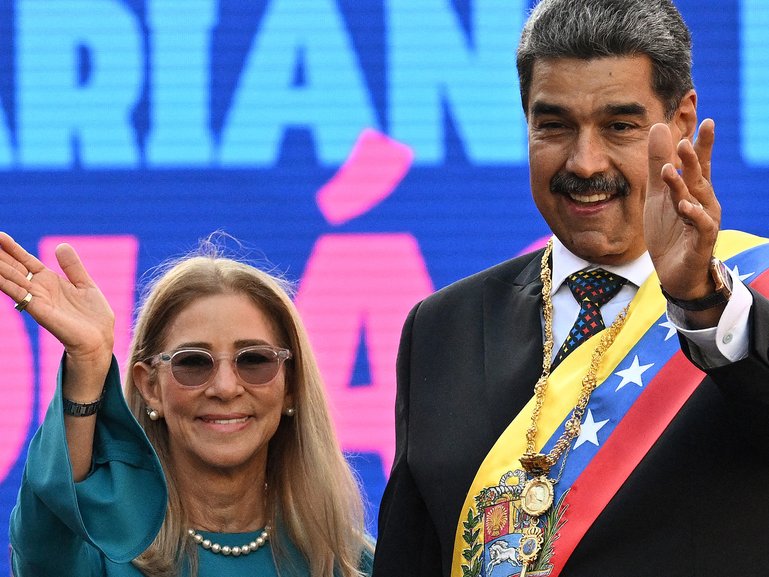 Venezuela's President Nicolas Maduro and his wife Cilia Flores wave to supporters in front of Miraflores presidential palace in Caracas on January 10, 2025. Maduro, in power since 2013, took the oath of office for a third term despite a global outcry that brought thousands out in protest on the ceremony's eve. (Photo by Federico PARRA / AFP)