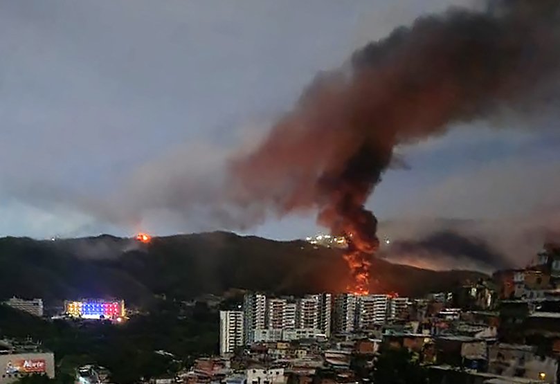 Fire at Fuerte Tiuna, Venezuela's largest military complex, is seen from a distance after a series of explosions in Caracas on January 3, 2026. 