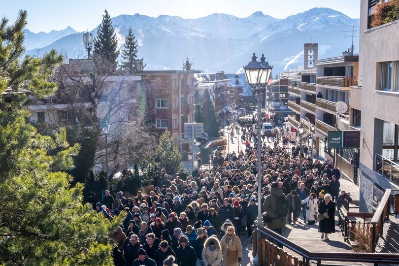 People walk after the memorial mass towards the Constellation bar to lay flowers, candles and messages at a makeshift memorial to pay their respects in Crans-Montana .