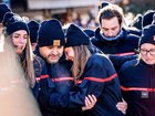 Firefighters from the Municipality of Crans-Montana react as they gather around a makeshift memorial to pay their respects by laying flowers, candles and messages near the Constellation bar, on January 4, 2026, in Crans-Montana in honour of the victims of the fire that ripped through the venue in the luxury Alpine ski resort on New Year's Eve. Authorities investigating the New Year's blaze in the Swiss resort of Crans-Montana have identified 24 of the 40 people killed, including 11 minors and six foreign nationals, police said on January 4, 2026. Also 119 were injured during the fire, most of them seriously, according to the latest toll. (Photo by MAXIME SCHMID / AFP)