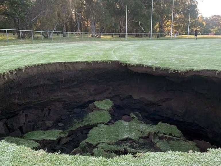 A massive sinkhole has opened up at a popular sports field, throwing local sports clubs into chaos as residents are urged to stay away. 