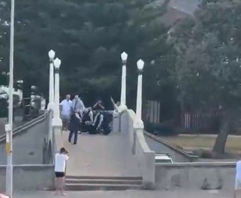 The Bondi shooter is approached by a man after he has been shot by police, who is filmed kicking the gun away.