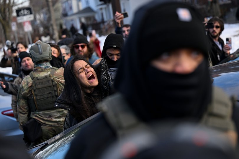 Federal agents remove a woman from a car after smashing her window, two blocks from where Good was fatally shot last week by an ICE officer.