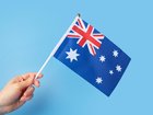 Australian flag in hand on a blue background, copy space, independence national day of Australia, country freedom, patriotism, banner 