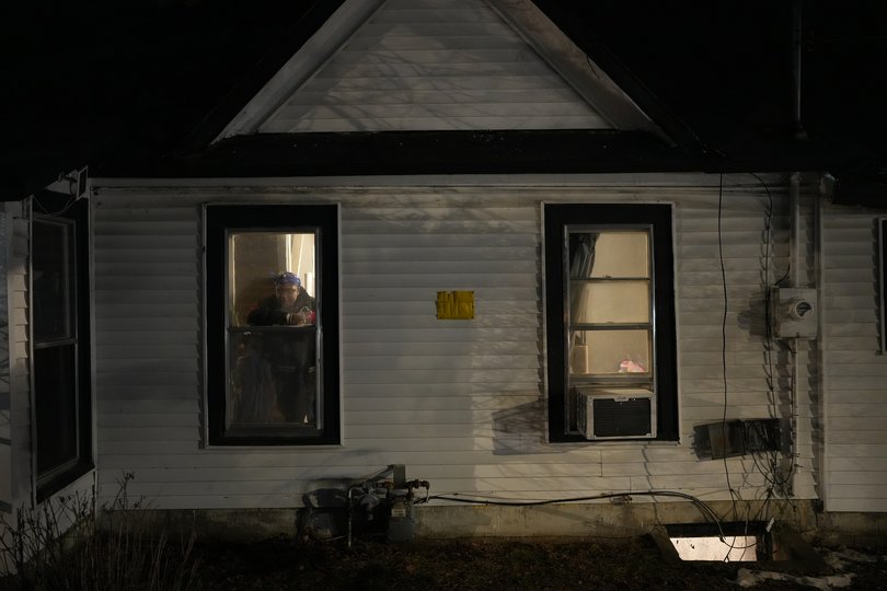 Residents watch from their windows as federal agents sweep through the streets of Minneapolis January 14.