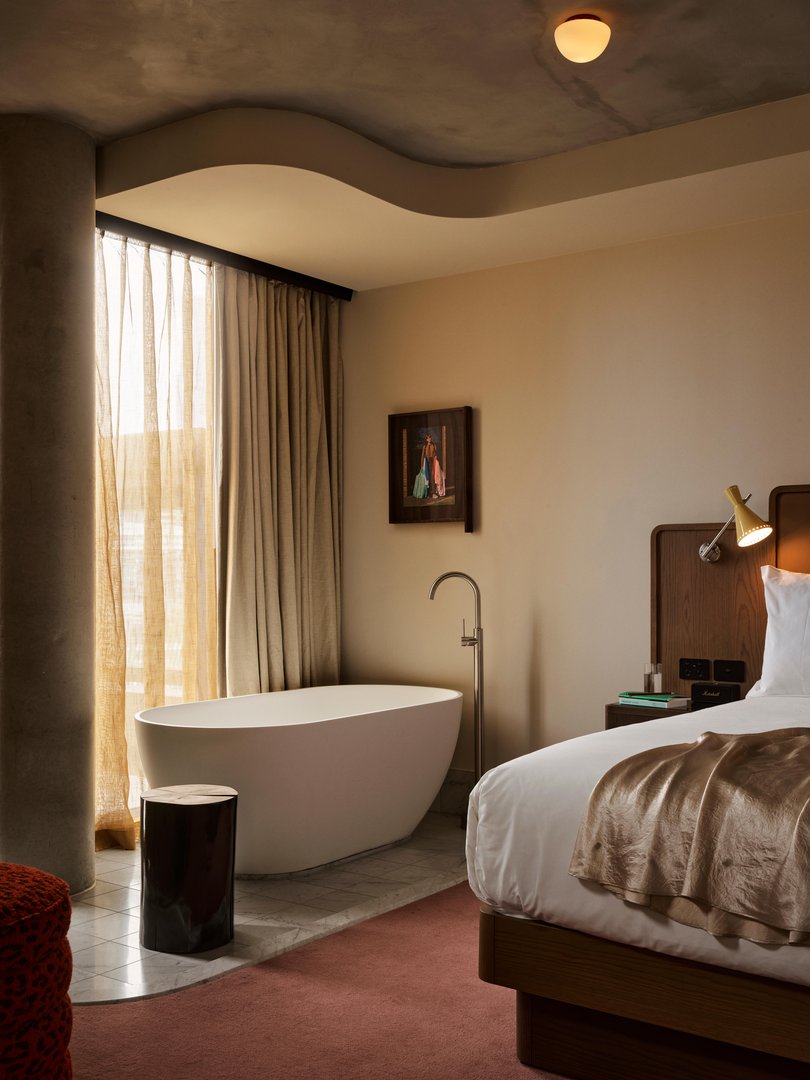 Blush-toned carpets, a private sitting room and a bold striped-tile bath define the suite’s playful luxury.