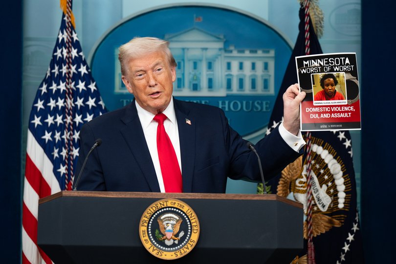 US President Donald Trump holds up a poster of a person apprehended by ICE.